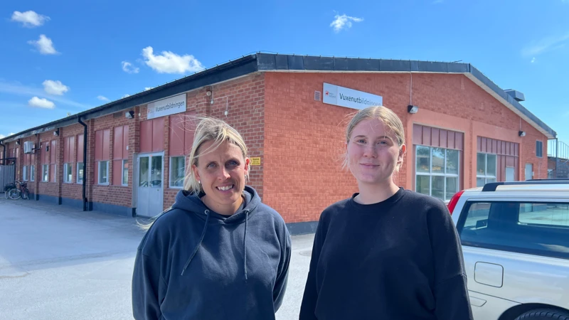 Två kvinnor som står framför en byggnad.