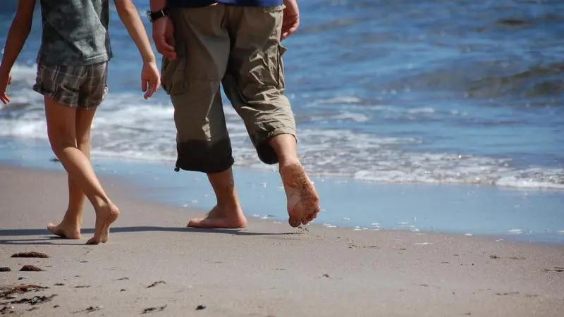 Två personer går på en strand