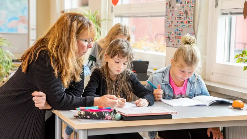Lärare hjälper två elever med uppgifter