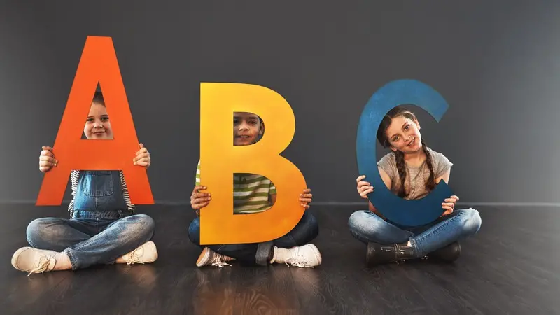 Barn sitter med bokstäverna ABC i knäet