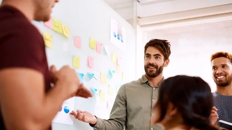 Personer som brainstormar framför en tavla med post-it-lappar