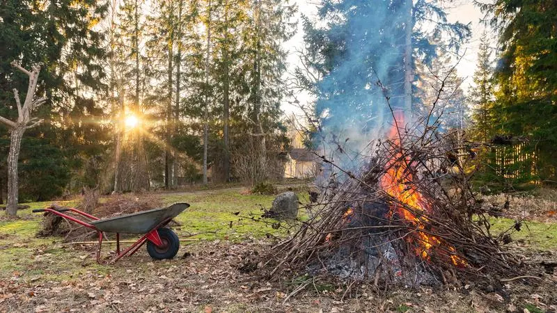 En skottkärra bredvid en brinnande rishög