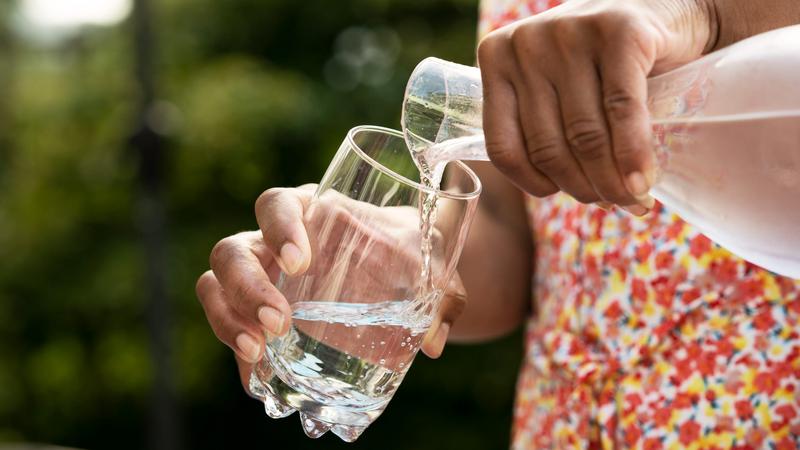 Kvinna häller upp ett glas vatten