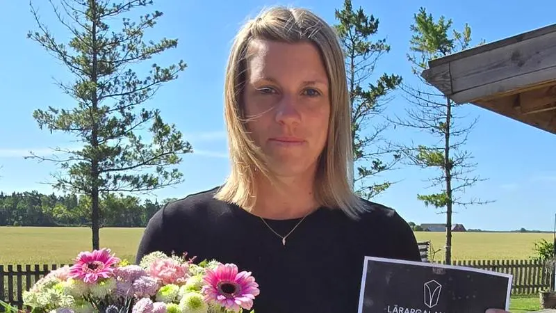 Kvinna utomhus med diplom och blombukett