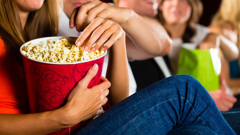 Händer som tar upp popcorn ur stor popcornskål