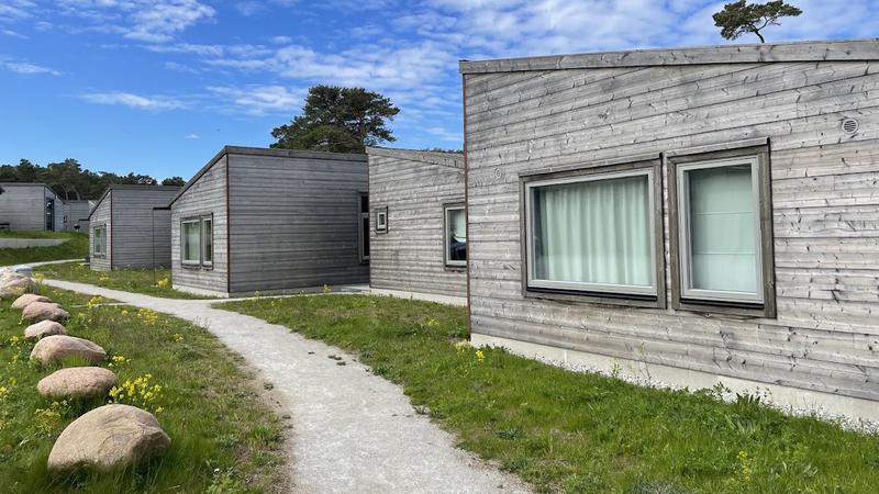 Stugor med grå träfasad och en grusgång