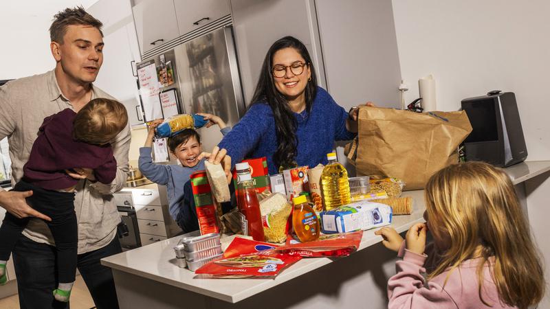 Barnfamilj i kök med köksbänken full av mat som håller länge