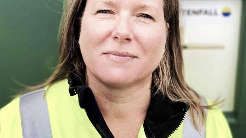 En kvinna i skyddsväst står framför ett kylskåp.