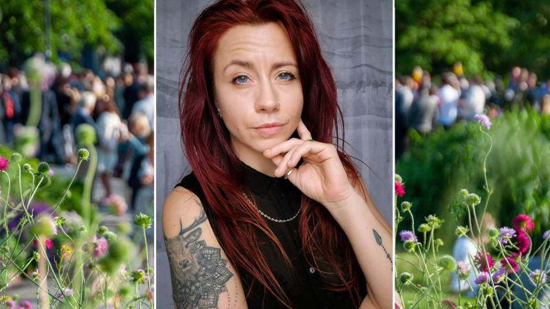 Kvinna med tatuering på armen tittar in i kameran. 