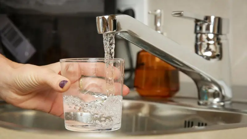Ett glas fylls på under vattenkran.