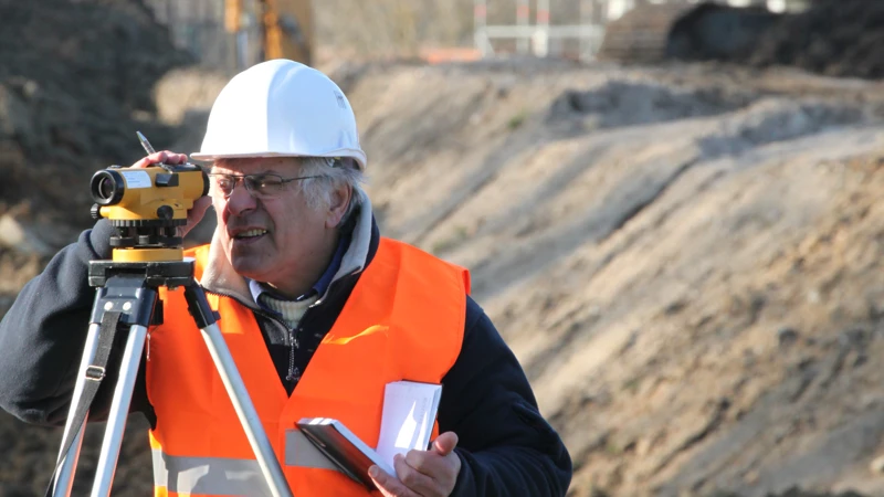 En man gör mätningar för markarbeten.