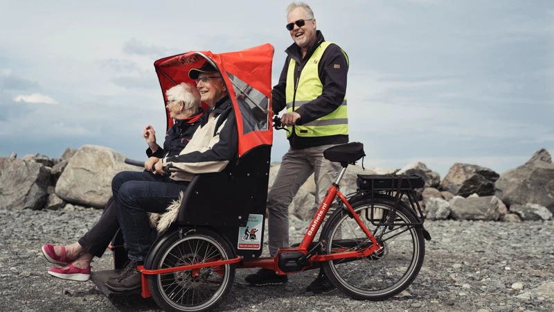 En man och en kvinna cyklar på en klippig strand.