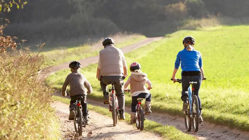 Familj cyklar längs en landsväg.