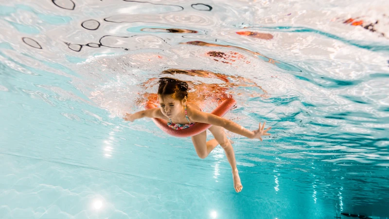 En ung flicka simmar i en pool.