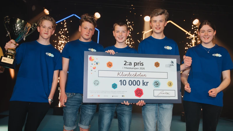 En grupp unga som står bredvid varandra och håller i en stor check.