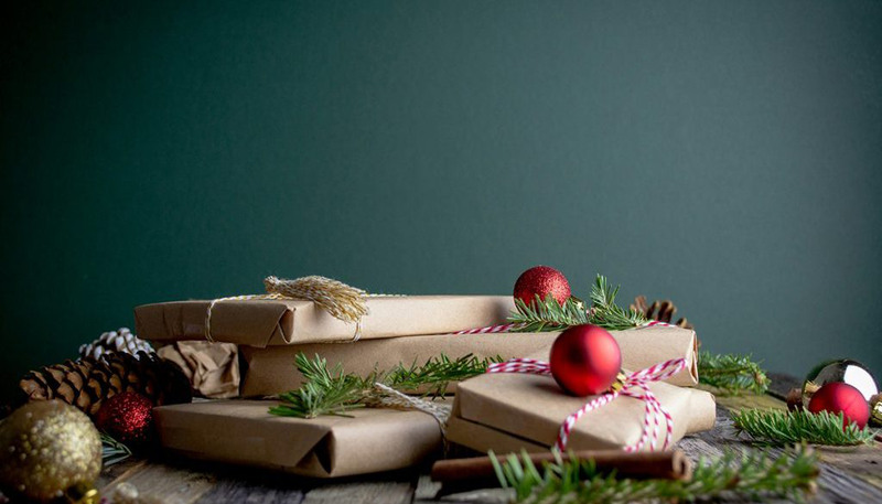 Julklappar inslagna i brunt papper med juldekorationer.