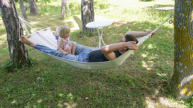 En vuxen man och ett barn sitter i en hängmatta.