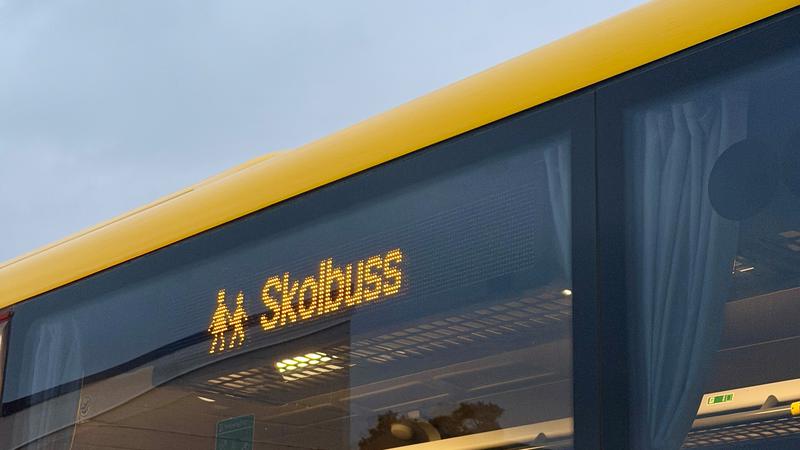 Detaljbild på en gul buss med texten "Skolbuss".