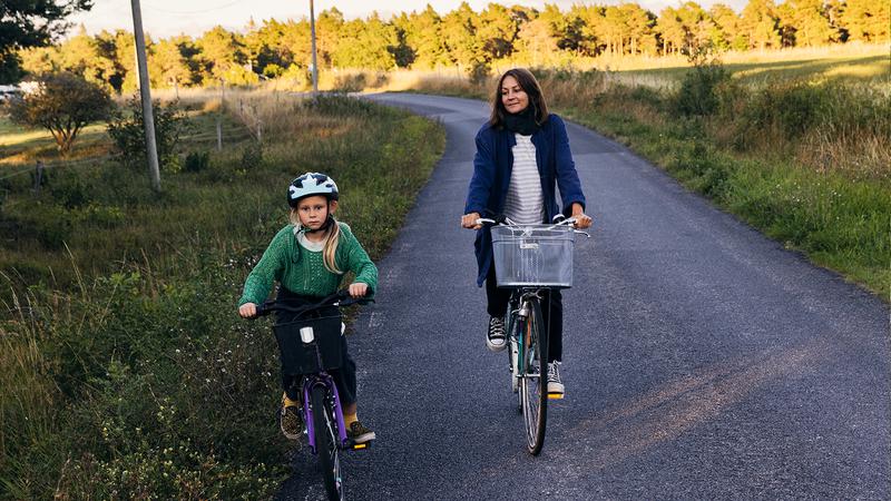 En kvinna cyklar bredvid ett barn på en cykel.