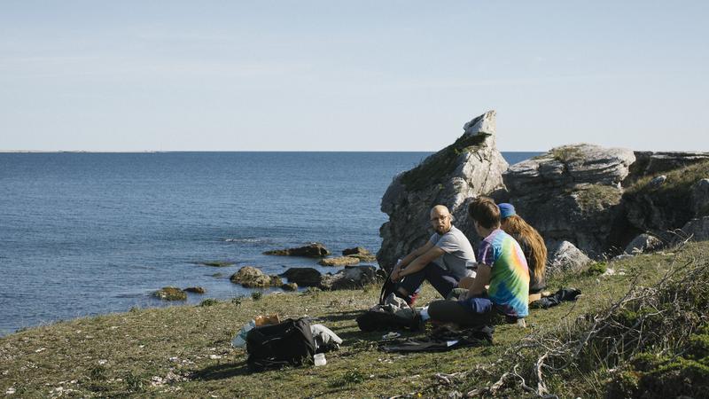 Tre personer sitter vid havet
