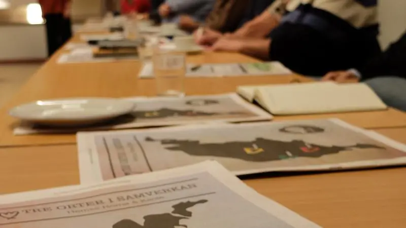 Bord med tidningar i förgrunden och personer i bakgrunden