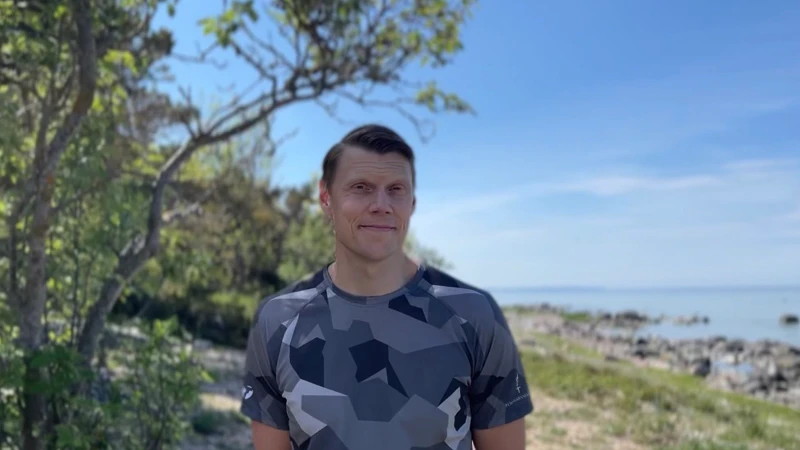 En man som står framför ett träd på en strand.