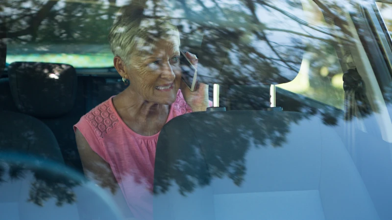äldre dam i bil, pratar i mobilen