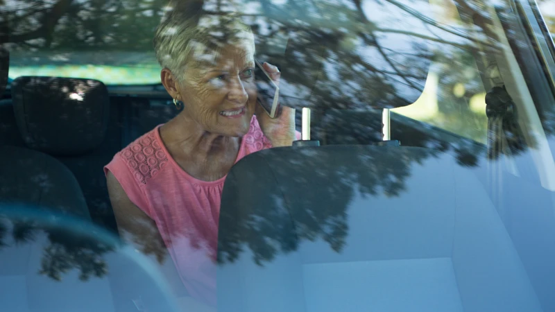 En kvinna som sitter i en bil och pratar i mobiltelefon.