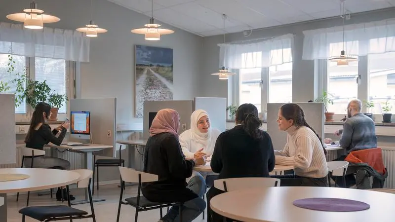 Elever som sitter vid borden i studieteket.