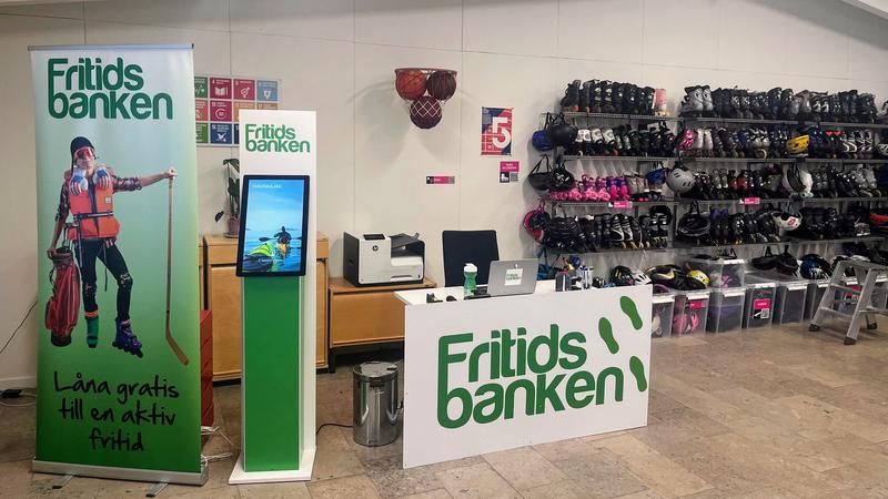 Rollup och skylt med texten Fritidsbanken och hylla med rullskridskor och utrustning