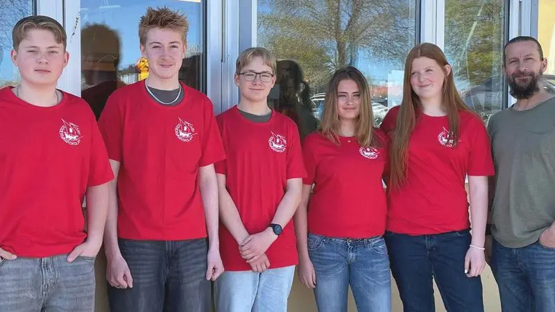 Fem elever i röda t-shirts står på rad tillsammans med sin mentor.