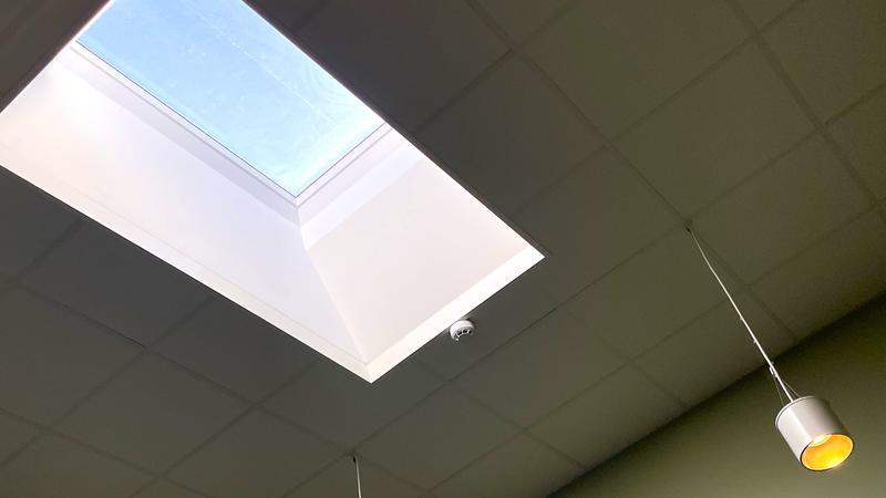 Stort takfönster i ett vitt tak med hängande lampa.