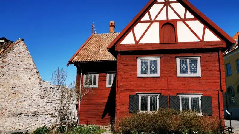 Gammalt rött hus intill ringmur.