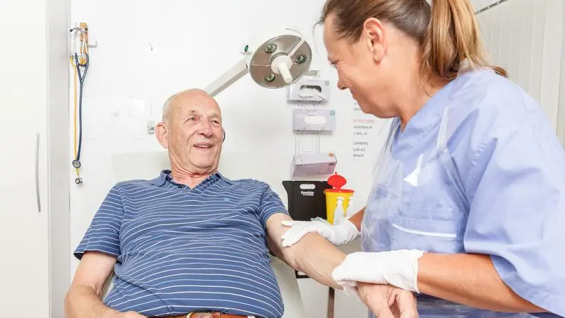 Sköterska sätter plåster på äldre patient