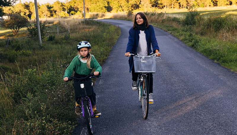 En kvinna på cykel bredvid en pojke på cykel.