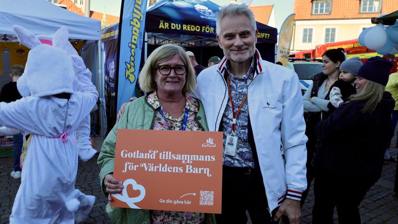 Två personer står och håller upp orange skylt.