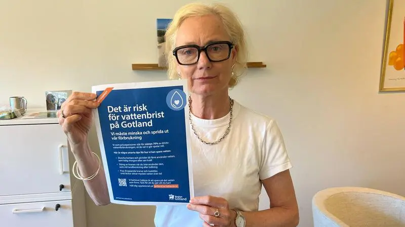 Kvinna håller upp en affisch med information om vattenbristen på Gotland.