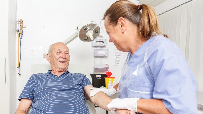 Sköterska sätter plåster på äldre patient