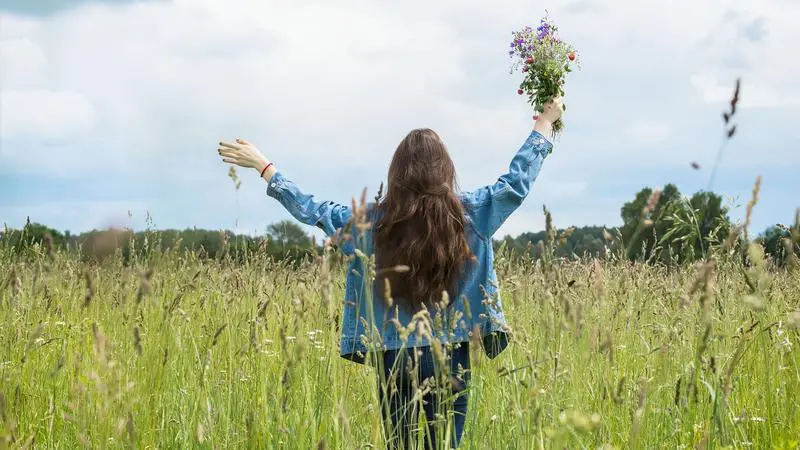 En kvinna står på ett fält och håller i en blombukett