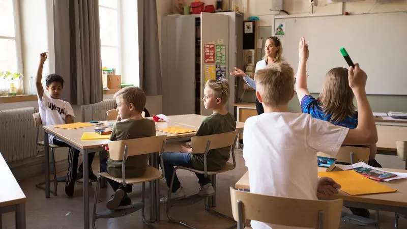Klassrum med mellanstadieelever som räcker upp handen