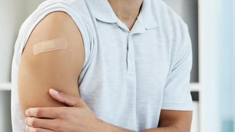Beskuren bild som visar en arm med plåster och en hand