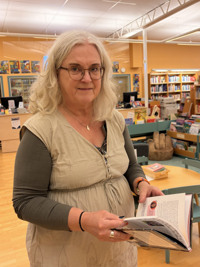 En kvinna som läser en bok på ett bibliotek.