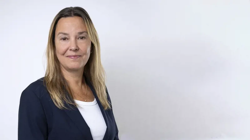 Kvinna i kavaj mot vit vägg