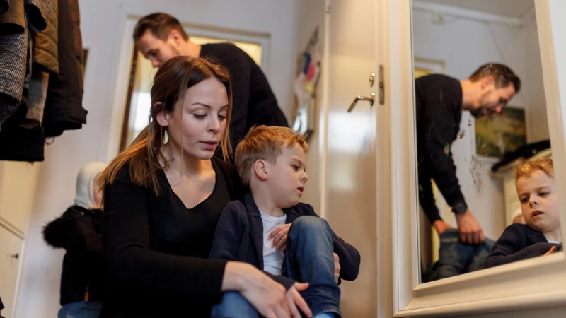 En kvinna sitter bredvid en pojke framför en spegel.