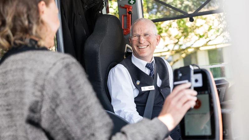 kvinnlig resenär blippar busskortet i mobilen, busschaufför