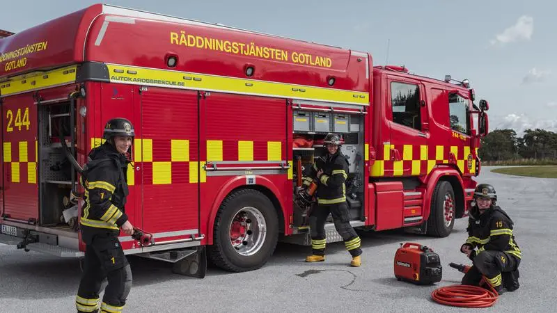Tre kvinnor framför en brandbil