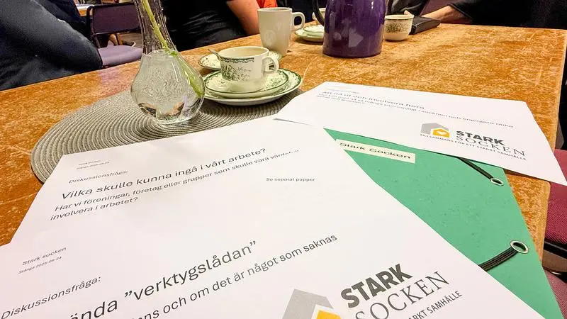 Dokument som ligger på ett bord, med kaffekoppar i bakgrunden