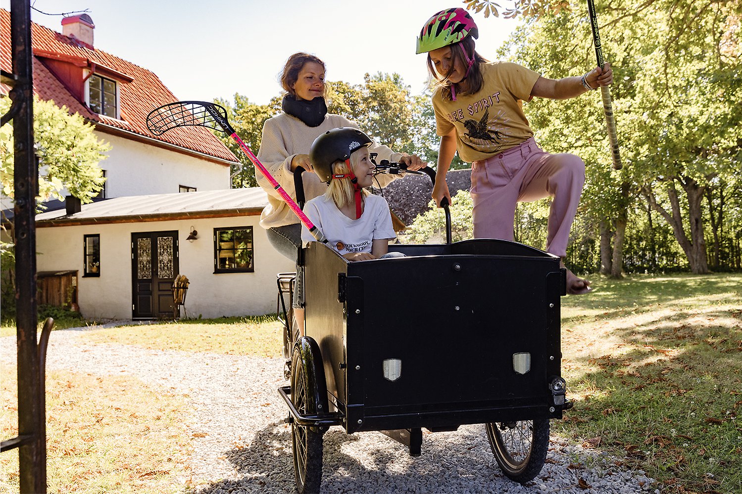 En kvinna med en lådcykel där  i två barn sitter
