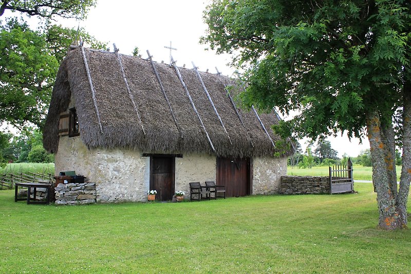 Ett gammalt stenhus med ett agtak och svarta trädörrar.