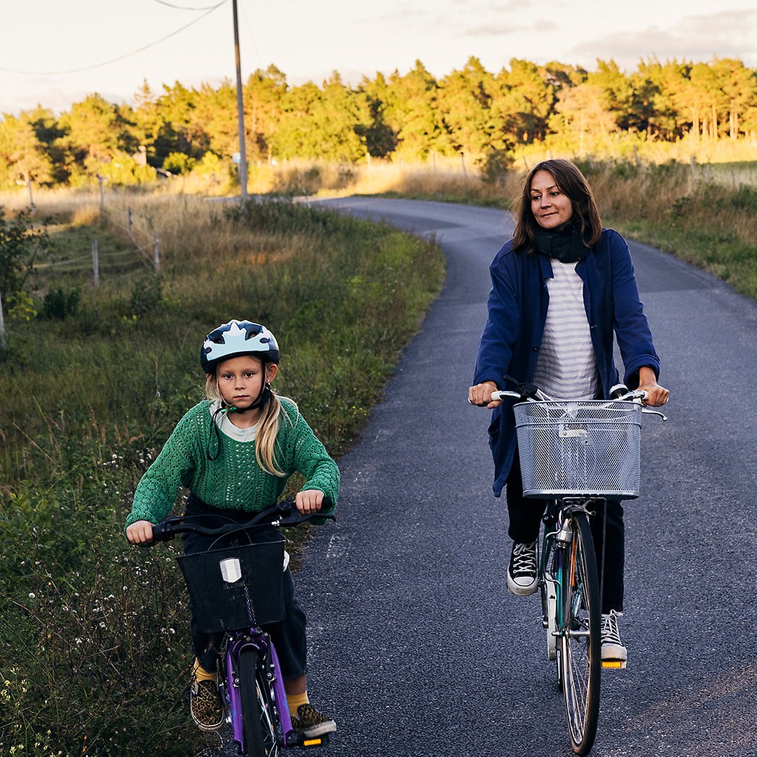 Kvinna och barn cyklar på landsväg